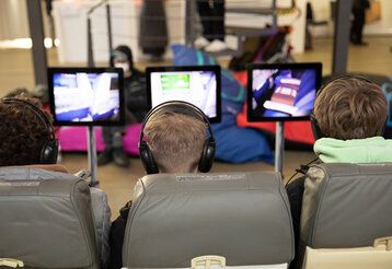 Drei Kinder von hinten, die Computerspiele spielen