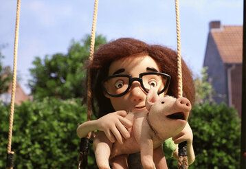 Stopp-Motion-Figur sitze mit einem Schweinchen auf einer Schaukel im Garten