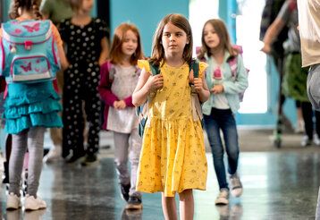 Junge geht mit einem gelben Kleid über einen Schulflur