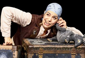 Schauspielerin als Pirat verkleidet hält sich das Bein einer Tierpuppe ans Ohr