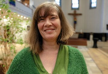 Nicole Mechtenberg steht in einer Kirche und lacht in die Kamera