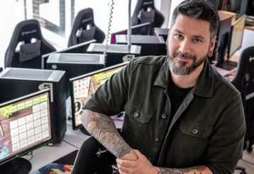 Porträt von Ben Schneider, im Hintergrund Gaming-Arbeitsplätze