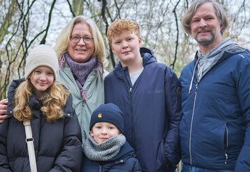 Vater, Mutter, eine Tochter, zwei Söhne vor winterlichen Bäumen