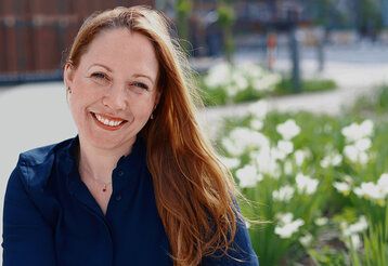 Porträt der Autorin Susanne Mierau, draußen, unscharfer Hintergrund, Platz mit Bepflanzung