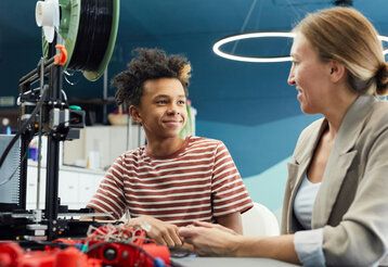 Junge sitzt mit Frau zusammen, in einem Studio, technische Geräte  liegen auf einem Tisch