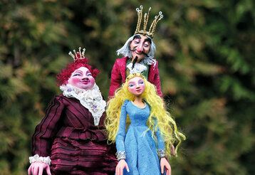 drei Handspielpuppen Königin, König, Prinzessin vor Gebüsch