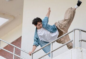 junger Mann springt an einem Geländer hoch