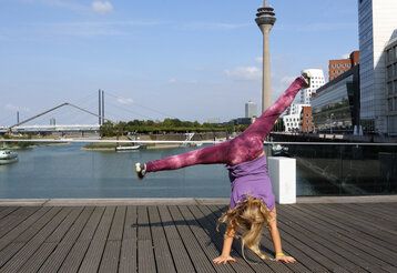 Mädchen, das einen Radschlag macht, im Hintergrund Medienhafen mit Fernsehturm