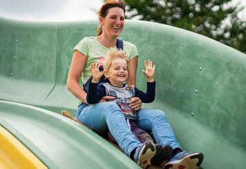 Mutter und Sohn rutschen lachend auf einer Rutsche im Bubenheimer Spieleland