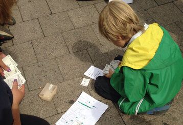 Junge hockt auf dem Boden und sortiert seine Fußball Sammelbilder