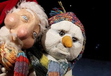 Puppen in Form von Weihnachtsmann und Schneemann gucken den Betrachter an, der Hintergrund ist schwarze Nacht