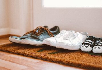 drei Paar Schuhe vor der Wohnungstür, von Vater, Mutter und Kleinkind