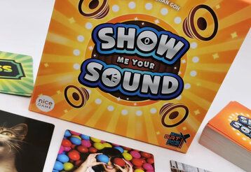 Verpackung des Spiels Show me your Sond mit Spielkarten, schräg fotografiert