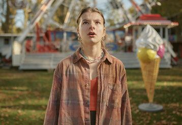 Mädchen steht auf einem Kirmesplatz und guckt stauenend nach oben