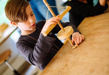 junge bastelt ein Amulette aus Holz