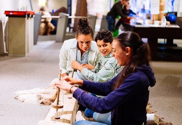 Zwei Kinder und ihre Mutter werkeln in der Steinzeitwerkstatt im Neanderthal Museum