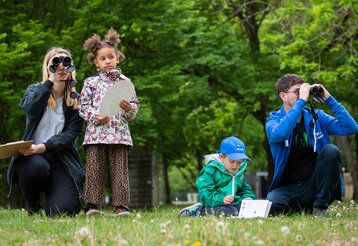 Vater, Mutter und zwei Kinder sind im Park und zählen Vögel