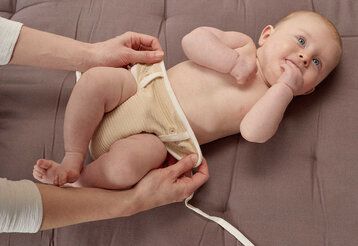 Baby wird mit Stoffwindel gewickelt