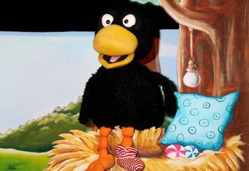 Szene aus dem Puppentheaterstück Rabe Socke, ein Rabe sitzt in seinem Nest