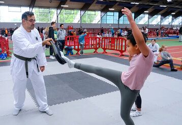 Ein Taekwondo-Lehrer übt mit einem Mädchen bei Kids in Action