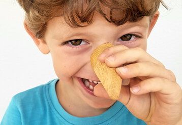 Junge hat Spass und macht eine lange Nase mit einer Eiswaffel