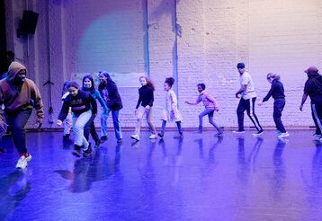 Ein Mann und einge Kinder und Jugendliche laufen in einem Raum hintereinander her