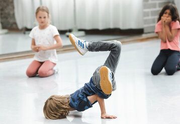 Junge macht Breakdance im Tanzhaus NRW, zwei Mädchen gucken zu