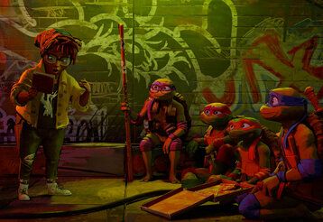 Teenage Mutant Ninja Turtles und ein Mädchen sitzen zusammen und essen eine Pizza, das Mädchen hält ein Buch in der Hand