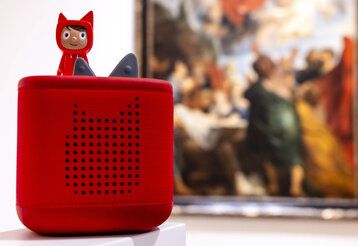 eine Tonies Box im Kunstpalast, im Hintergrund ein großes Ölgemälde