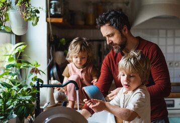 Vater mit zwei Kindern in der Küche beim Abspülen
