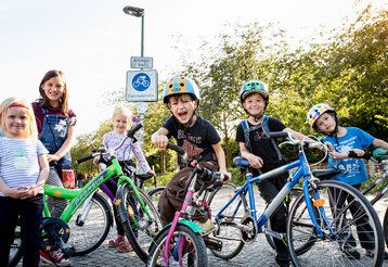 drei Mädchen und drei Jungen stehen mit ihren Fahrrädern auf einer Straße