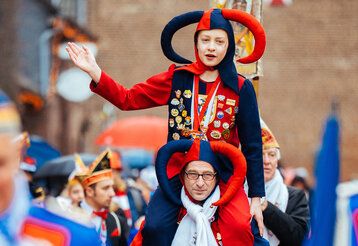 Als Narr erkleideter Vater trägt verkleideten Sohn beim Monheimer Karneval Huckepack
