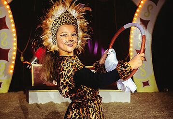 Verkleidestes Mädchen mit einer weißen Taube im Winterzirkus
