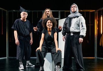 drei Schauspieler und eine Schauspielerin stehen auf einer dunklen Bühne