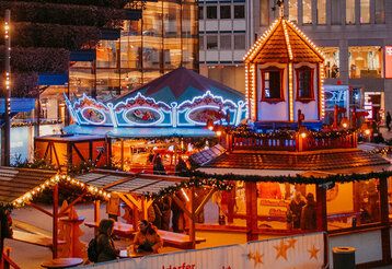 Beleuchtete Weihnachtsmarktstände am Köbogen in der Dämmerung