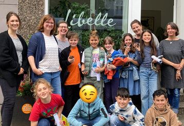 Gruppenbild: Schüler der Zeitungs AG der Lenne Schule mit Mitarbeiterinnen der Libelle, vor dem Ladenlokal der Redaktion