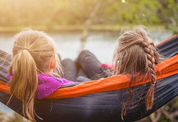 Zwei Mädchen von hinten in einer Hängematte