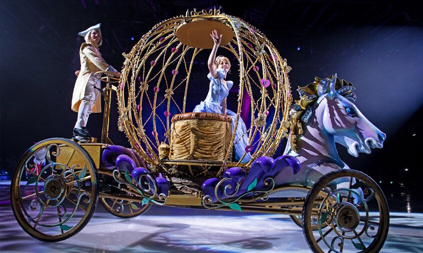 Cinderella fährt in einer Kutsche übers Eis und winkt