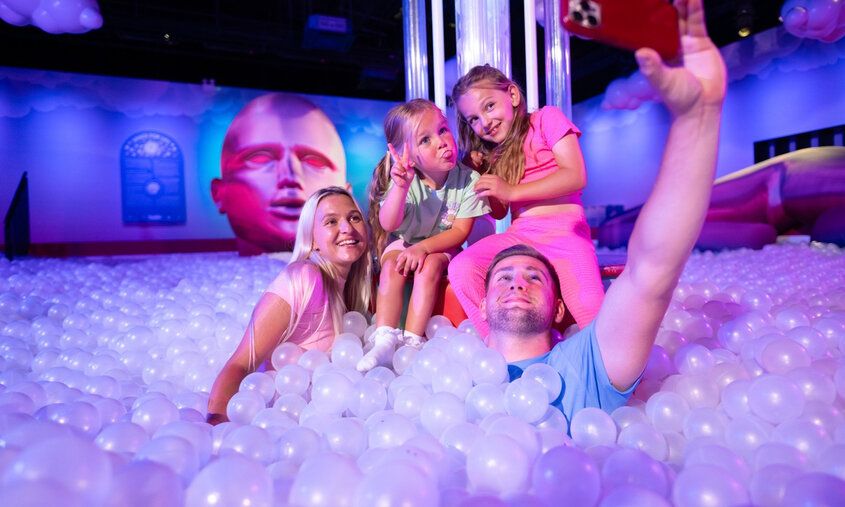Vater, Mutter und zwei Töchter in einem Bällebad im Bubble Planet