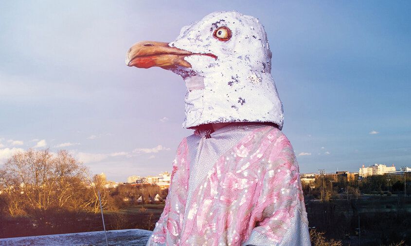 Schasuspieler mit Pinguinmaske, im Hintergrund Hochhäuser