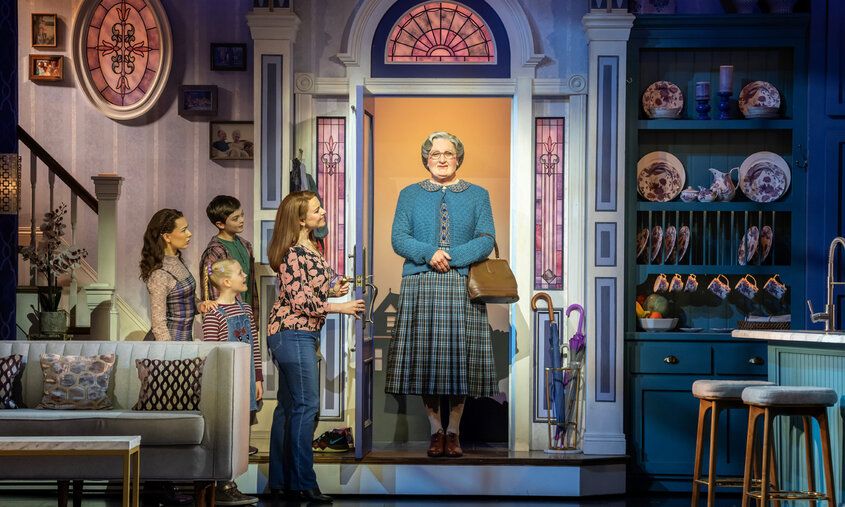 Szene aus dem Musical Mrs Doubtfire, Mrs Doubtfire steht in der Haustür und wird von der Familie begrüßt