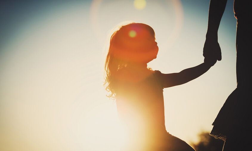 Kind an der Hand der Mutter, im Gegenlicht fotografiert mit Sonnenflecken