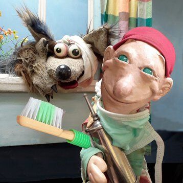 Kasperle und der Wolf stehen vor dem Bühnenbild