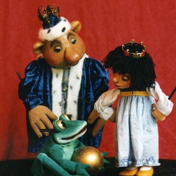 Die Hauptdarsteller aus dem "Froschkönig" als Puppen vor einer roten Wand