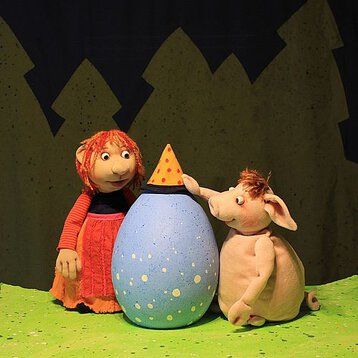 Eine kleine Hexe und ein Schweinchen bewundern ein himmelblaues großes Ei in ihrer Mitte