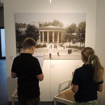 Zwei Kinder betrachten ein Foto in der Ausstellung der Römerthermen Zülpich